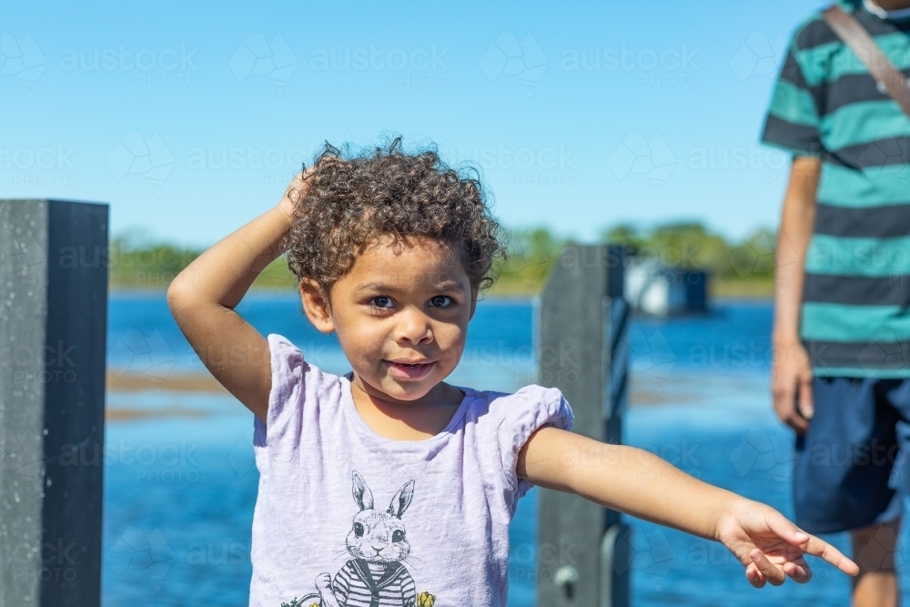 little kid with curly hair pointing to something out of frame - Australian Stock Image
