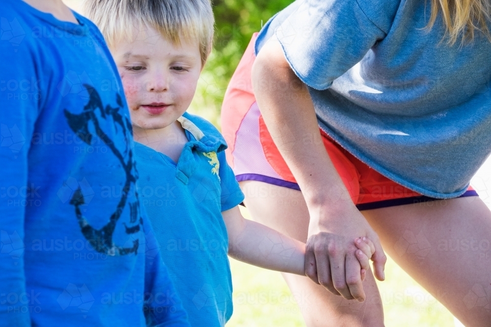 Little toddler holds hands with the bigger kids - Australian Stock Image