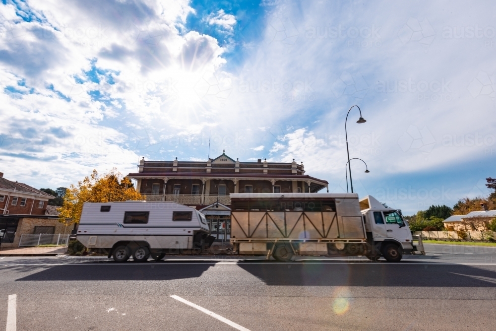 Livestock truck towing caravan past historic pub in Uralla in the Northern Tablelands - Australian Stock Image