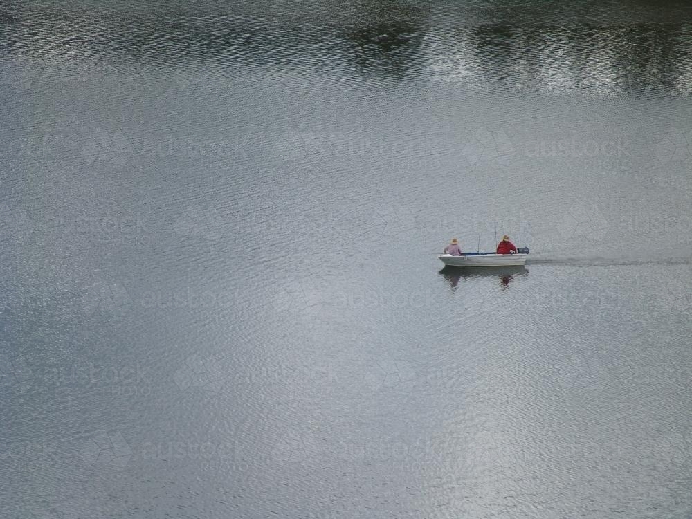 Lone boat motoring across a body of water - Australian Stock Image