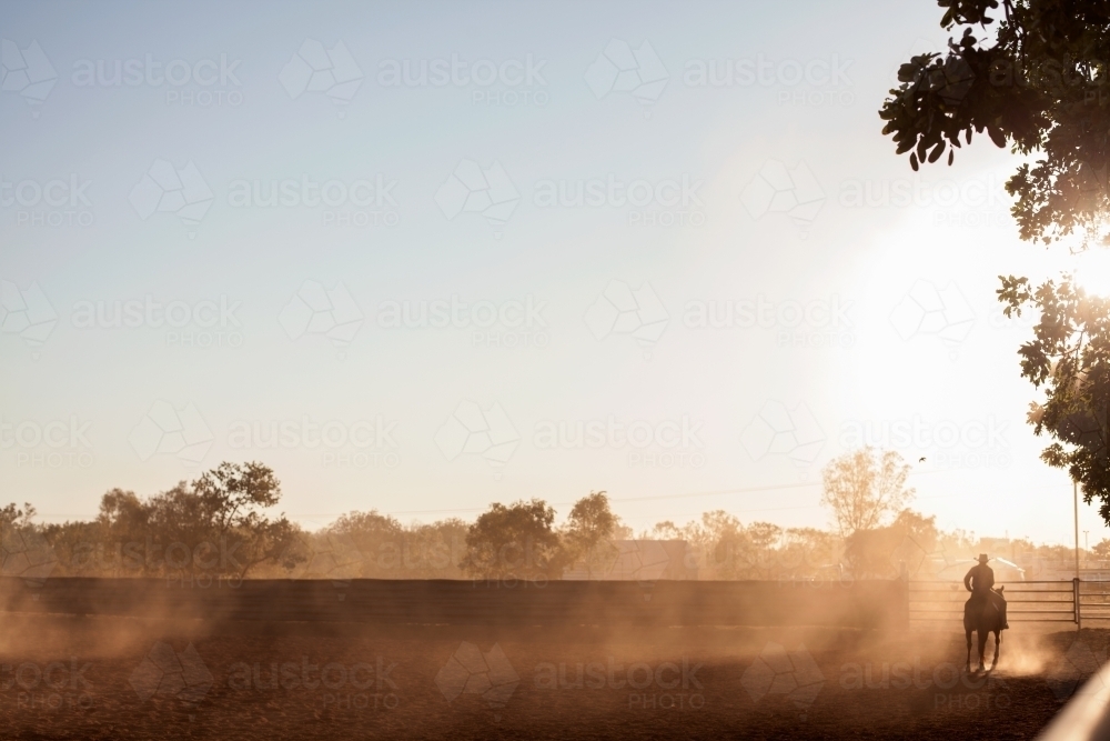 Lone rider in dusty yard - Australian Stock Image