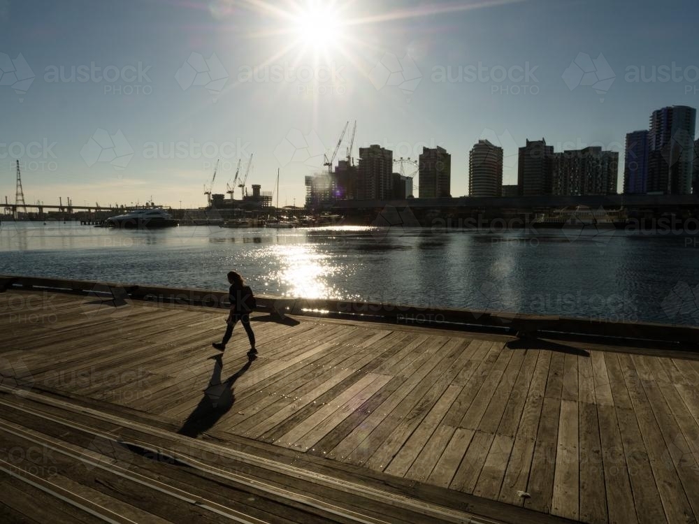 Lone Woman walking along boardwalk in city - Australian Stock Image