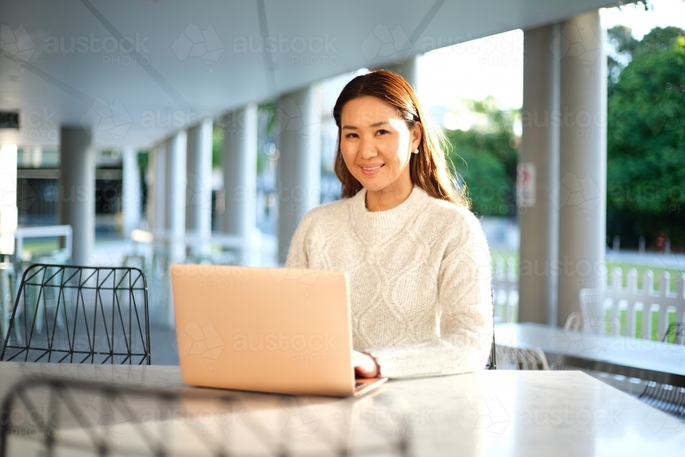 Lone woman working on laptop in seated area - Australian Stock Image