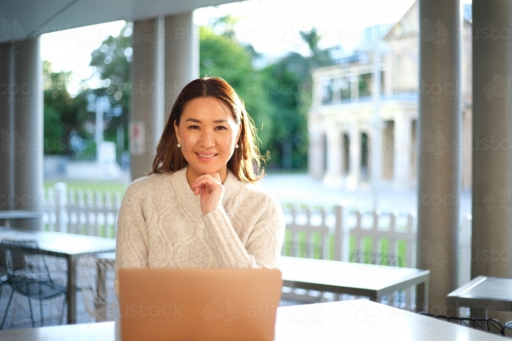 Lone woman working on laptop in seated area - Australian Stock Image