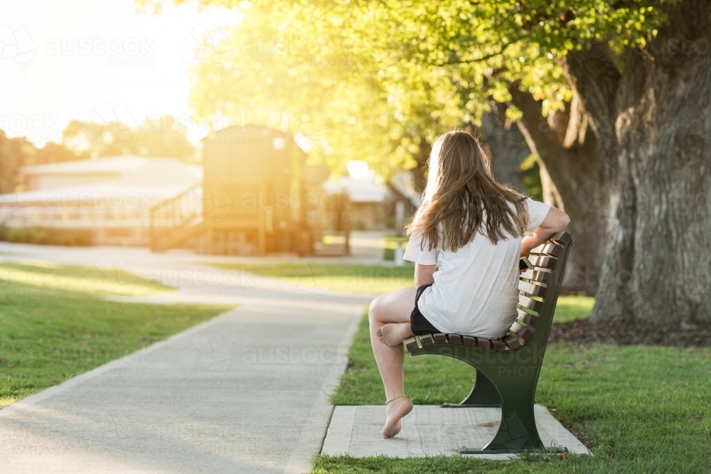Lonely teenage girl on a park bench - Australian Stock Image