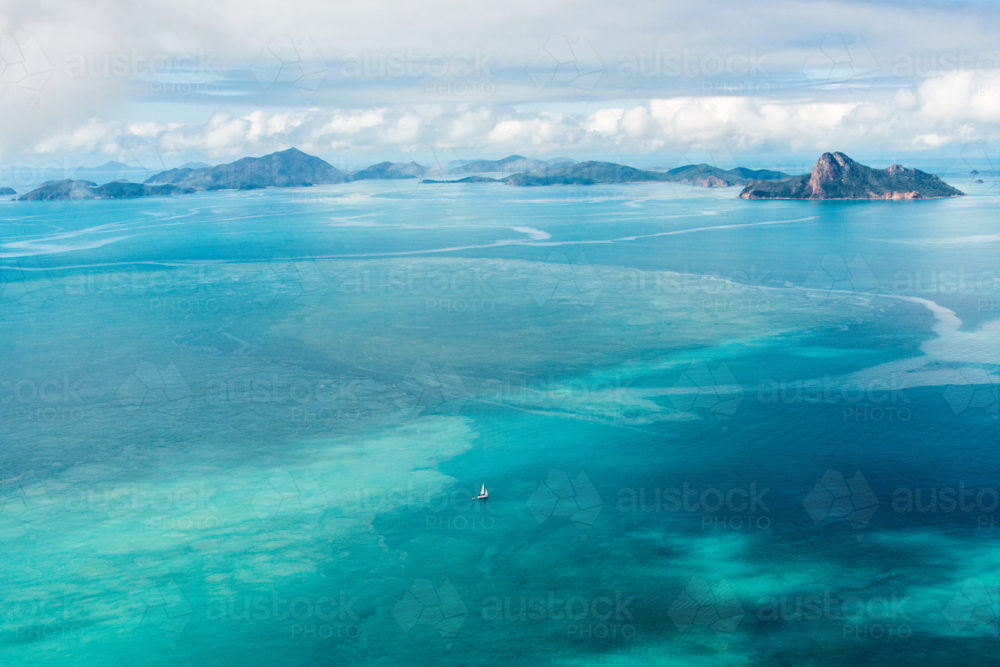 Lonely yacht drifting over turquoise reef waters - Australian Stock Image
