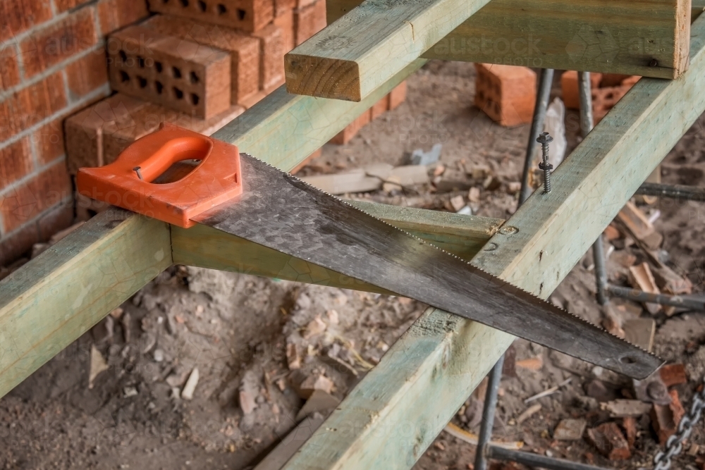 Long blade hand saw resting on timber struts at building site - Australian Stock Image
