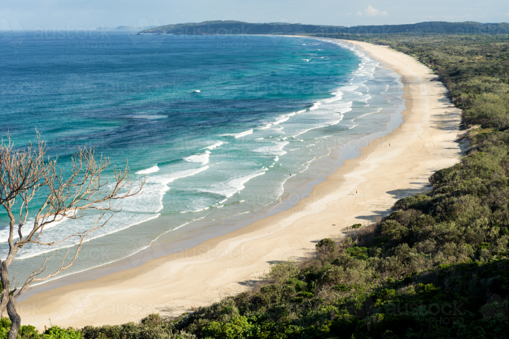 Long curve of sand and surf at Tallows Beach near Byron Bay - Australian Stock Image