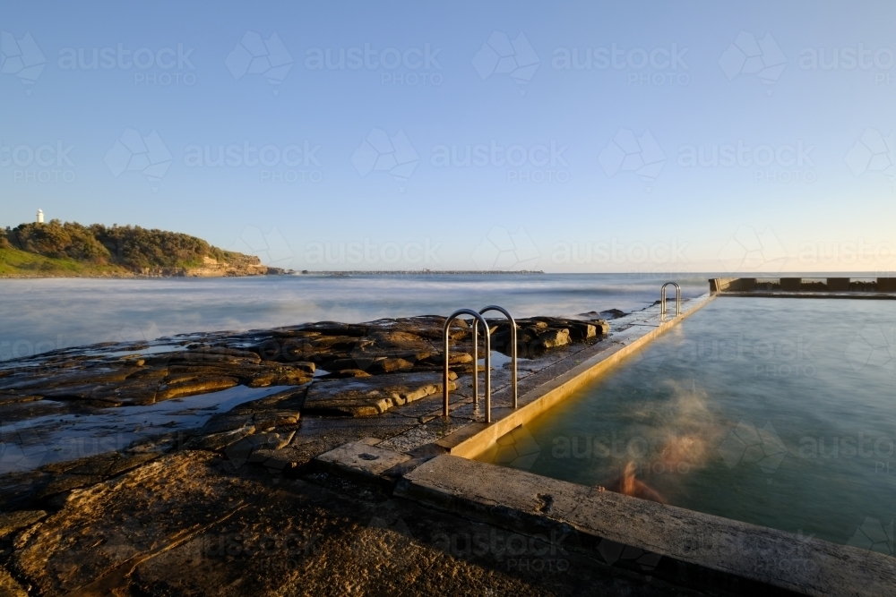 Long exposure of a swimmer in the ocean pool at Yamba - Australian Stock Image