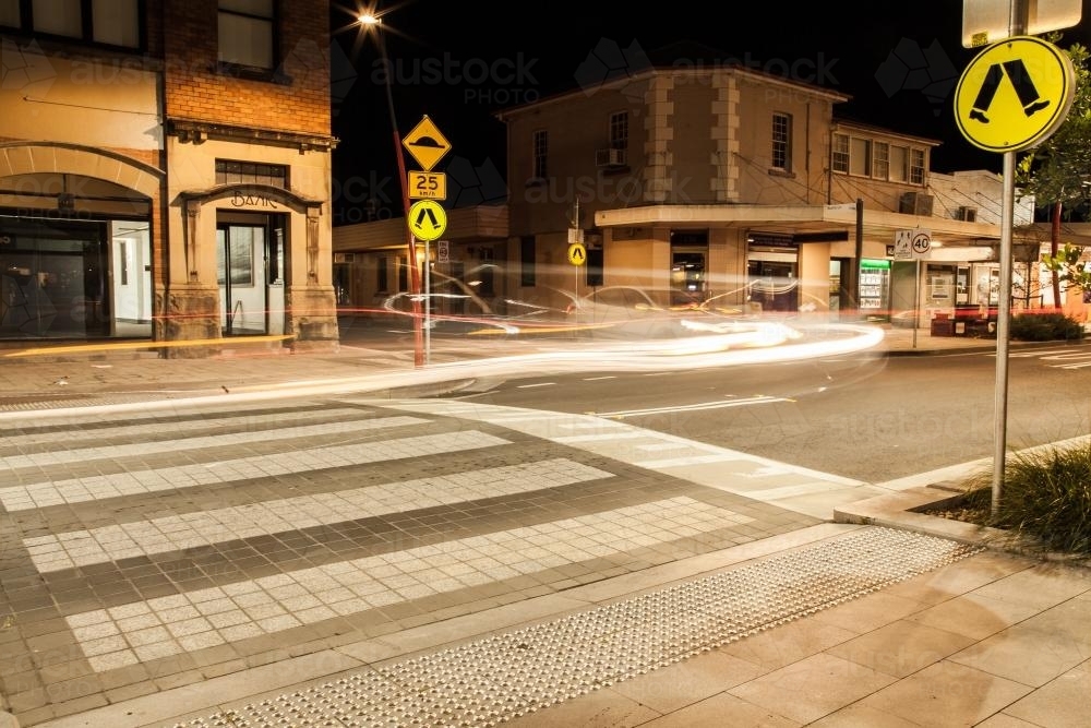 Long exposure of pedestrian crossing with car light trails at night - Australian Stock Image