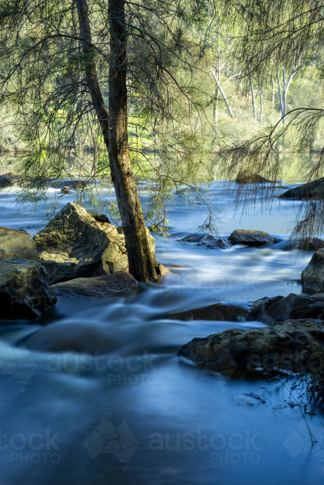 Long exposure of river winding around boulders - Australian Stock Image