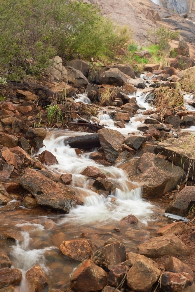 Long exposure of water flowing down rocky stream near Lesmurdie Falls, Perth, Western Australia - Australian Stock Image