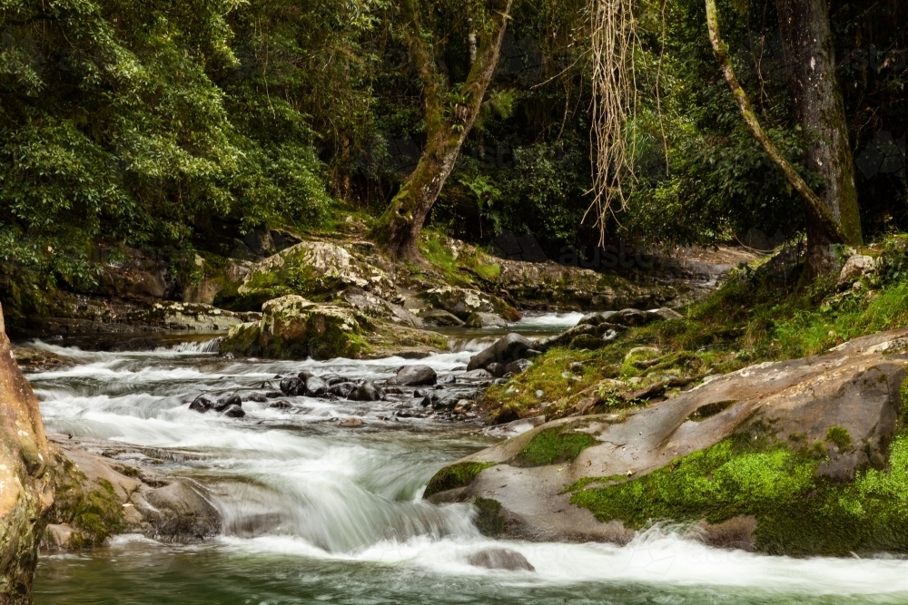 Long exposure of waterfall with smooth water running over river rocks - Australian Stock Image