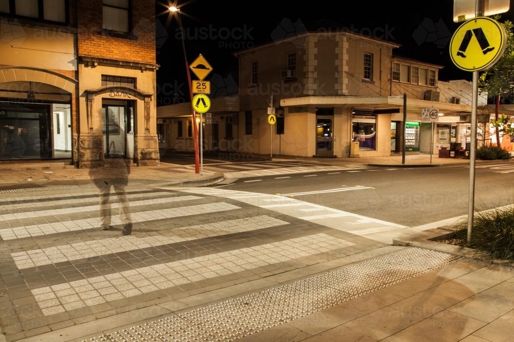 Long exposure of young woman walking over a pedestrian crossing - Australian Stock Image