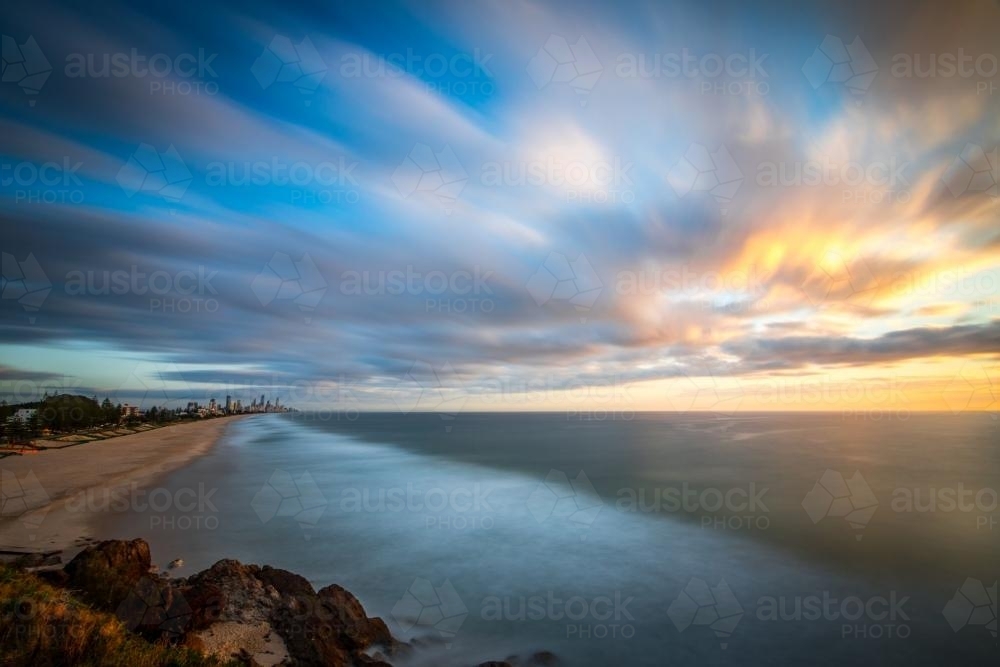 Long exposure view over beach and ocean with streaky clouds - Australian Stock Image