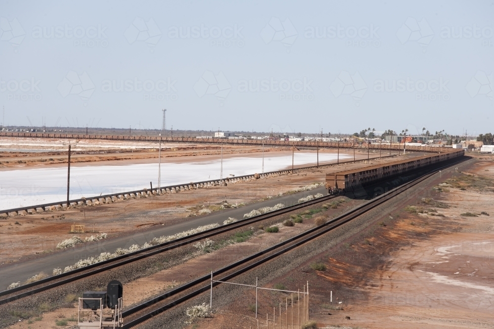 long goods train running beside salt lake - Australian Stock Image