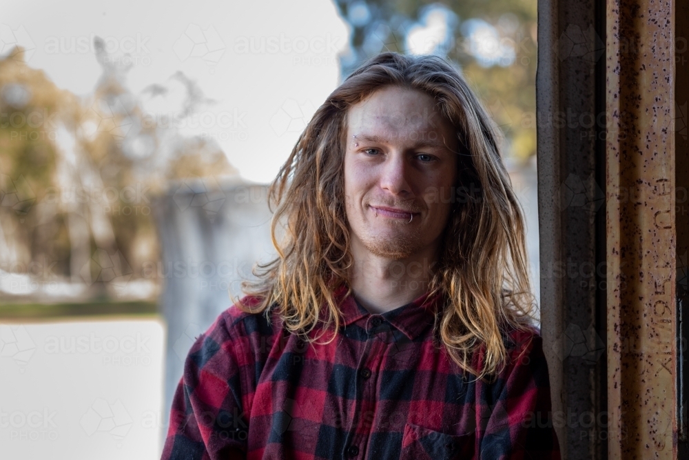 long-haired bloke leaning in shed doorway - Australian Stock Image