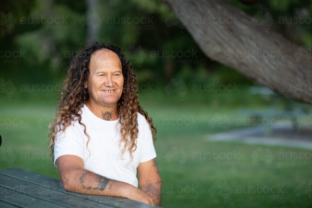 long-haired middle-aged man in white tee-shirt - Australian Stock Image