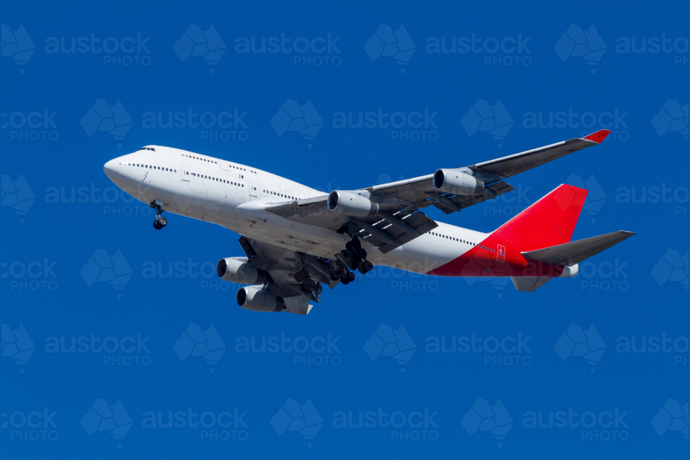 Long-haul 747 jumbo jet airplane viewed obliquely from underneath. - Australian Stock Image