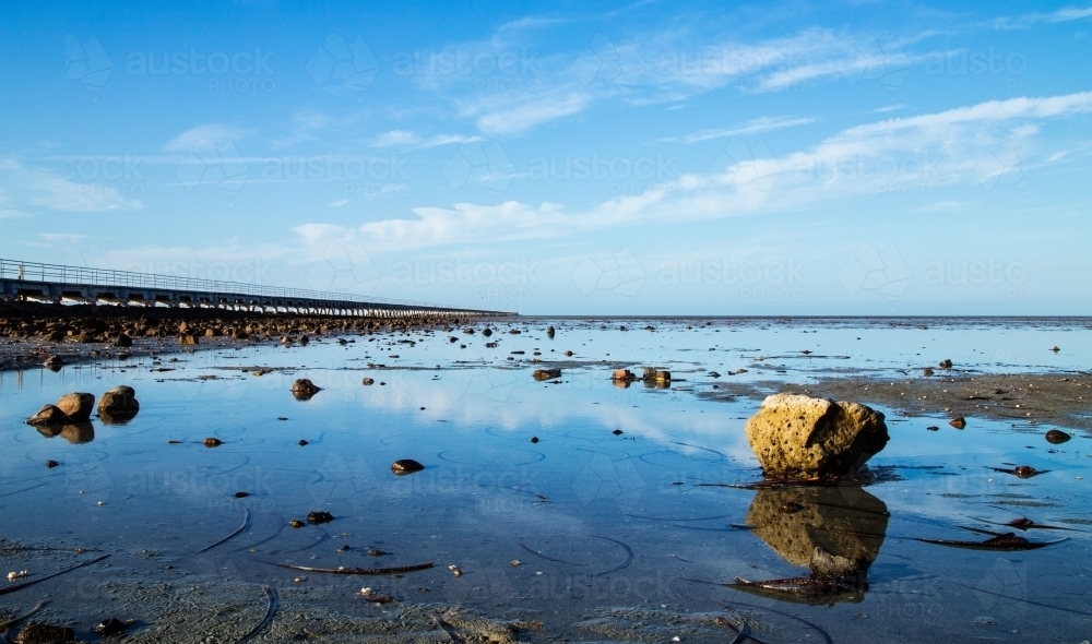 long jetty with reflections in shallow water - Australian Stock Image