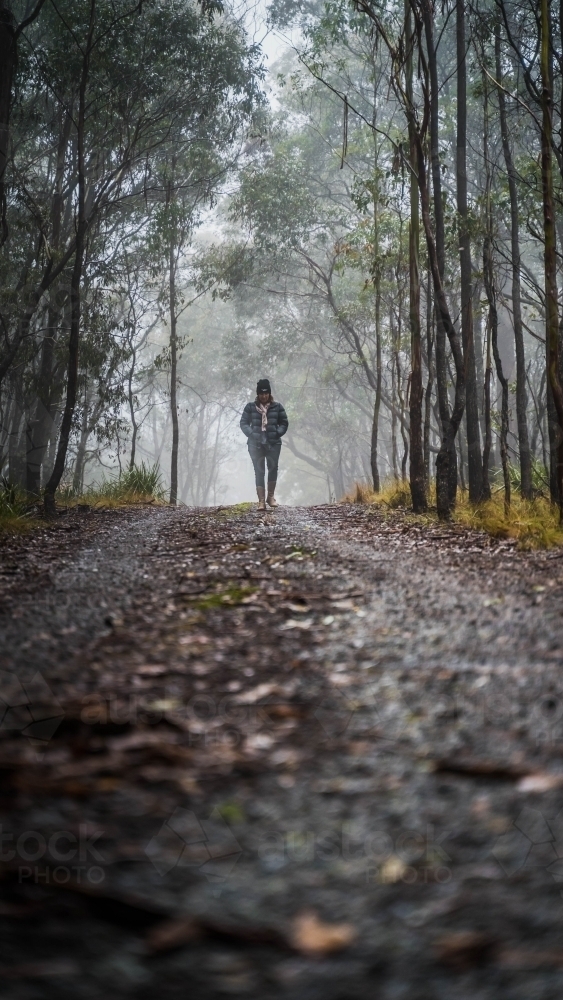 Long view of woman walking through foggy mountain track - Australian Stock Image