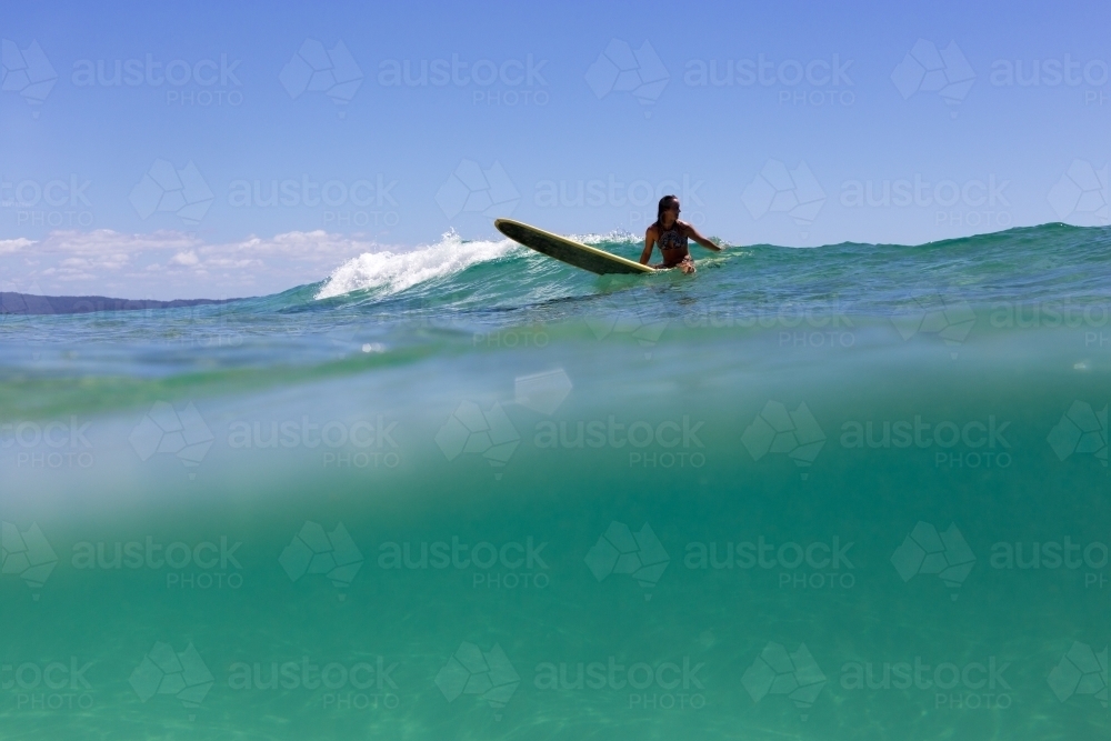 Longboard surfer waiting for a wave in turquoise water - Australian Stock Image