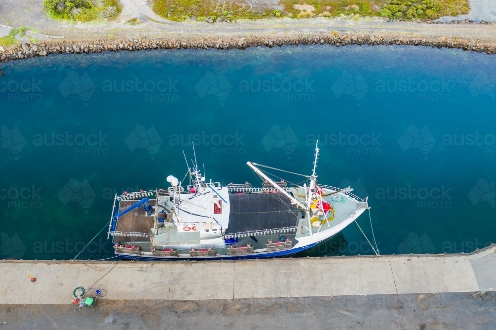 Looking down a solitary fishing boat docked in a coastal channel - Australian Stock Image