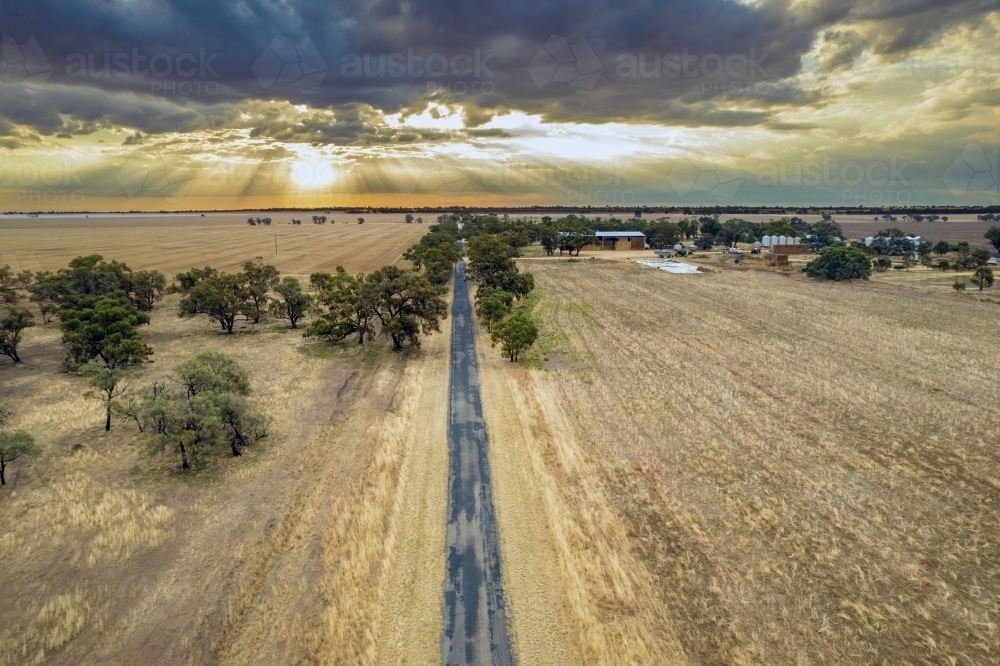 Looking down along the road with the sun setting behind the clouds - Australian Stock Image