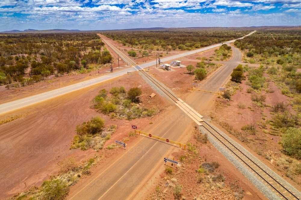 Looking down at asphalt road and railway crossing on the red terrain earth - Australian Stock Image