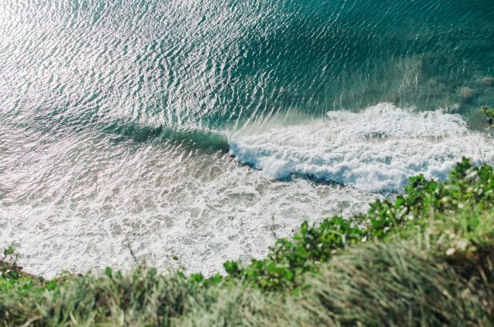 Looking down at green waves rolling in over beach - Australian Stock Image