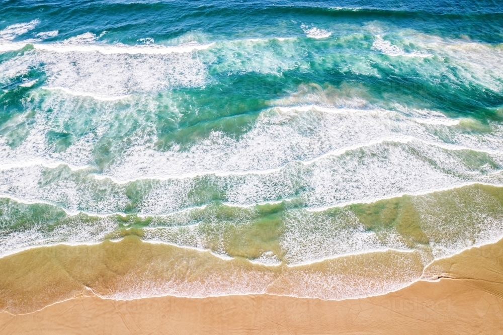 Looking down at ocean colours as the water flows into the sand. - Australian Stock Image
