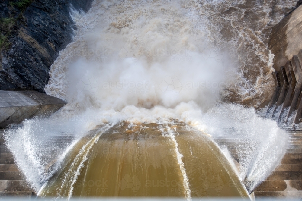 Looking down at over flowing dam as water gushes to the bottom - Australian Stock Image