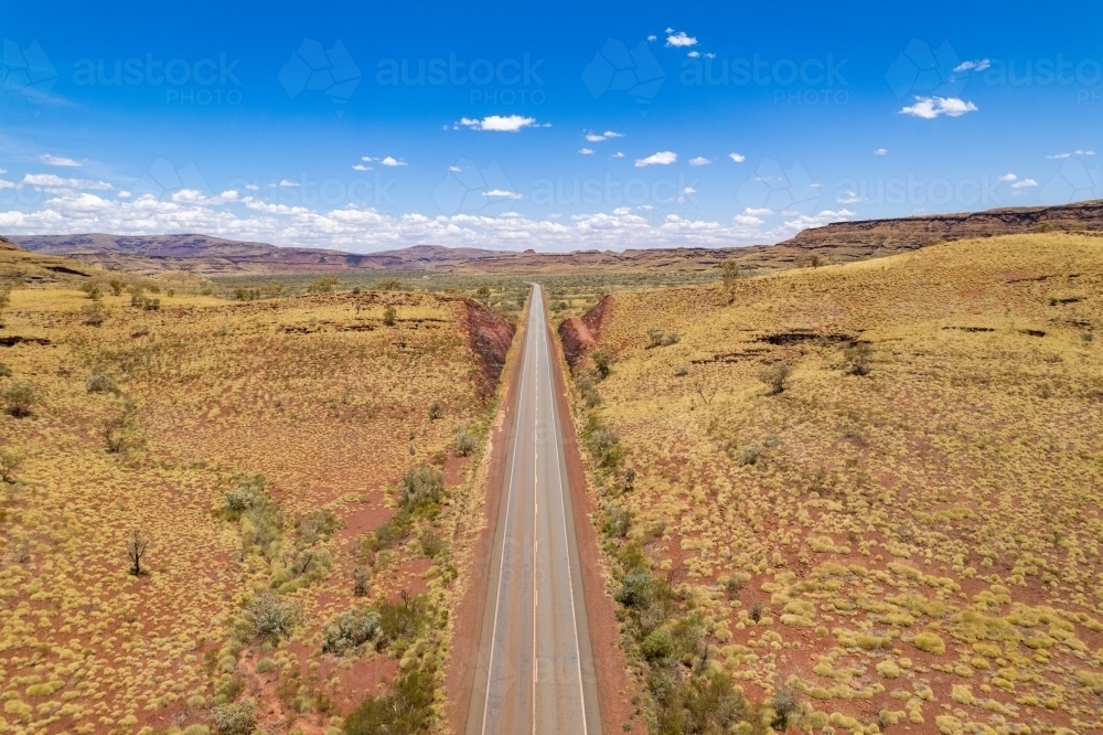 Looking down at straight asphalt road at the red terrain earth - Australian Stock Image