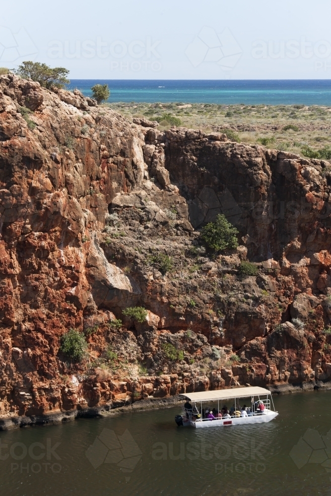 Looking down from cliff to tourist boat in remote gorge - Australian Stock Image