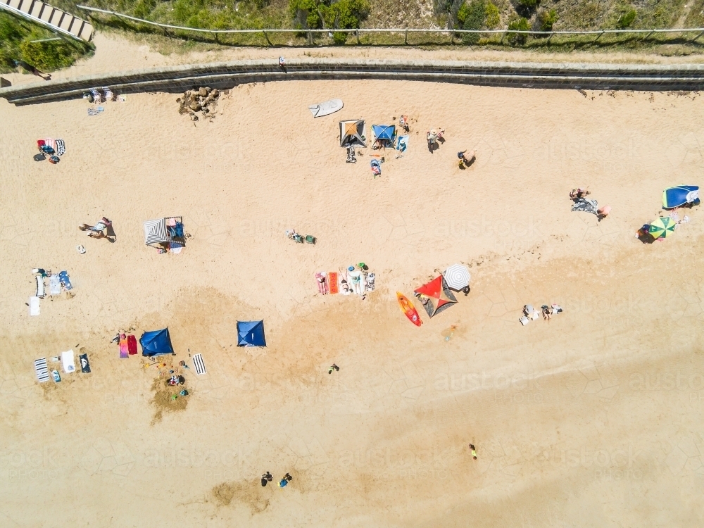 Looking down on a beach sandy beach at umbrellas, towels and beachgoers - Australian Stock Image