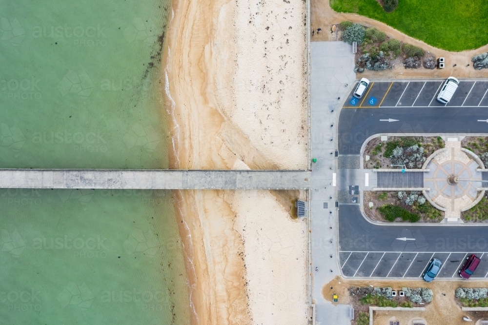 Looking down on a car park leading out onto a narrow jetty over a beach - Australian Stock Image