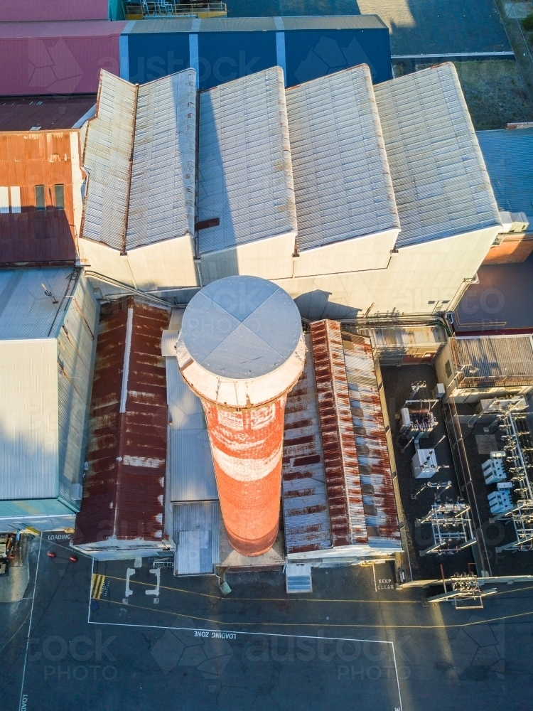 Looking down on a factory roof and brick chimney - Australian Stock Image