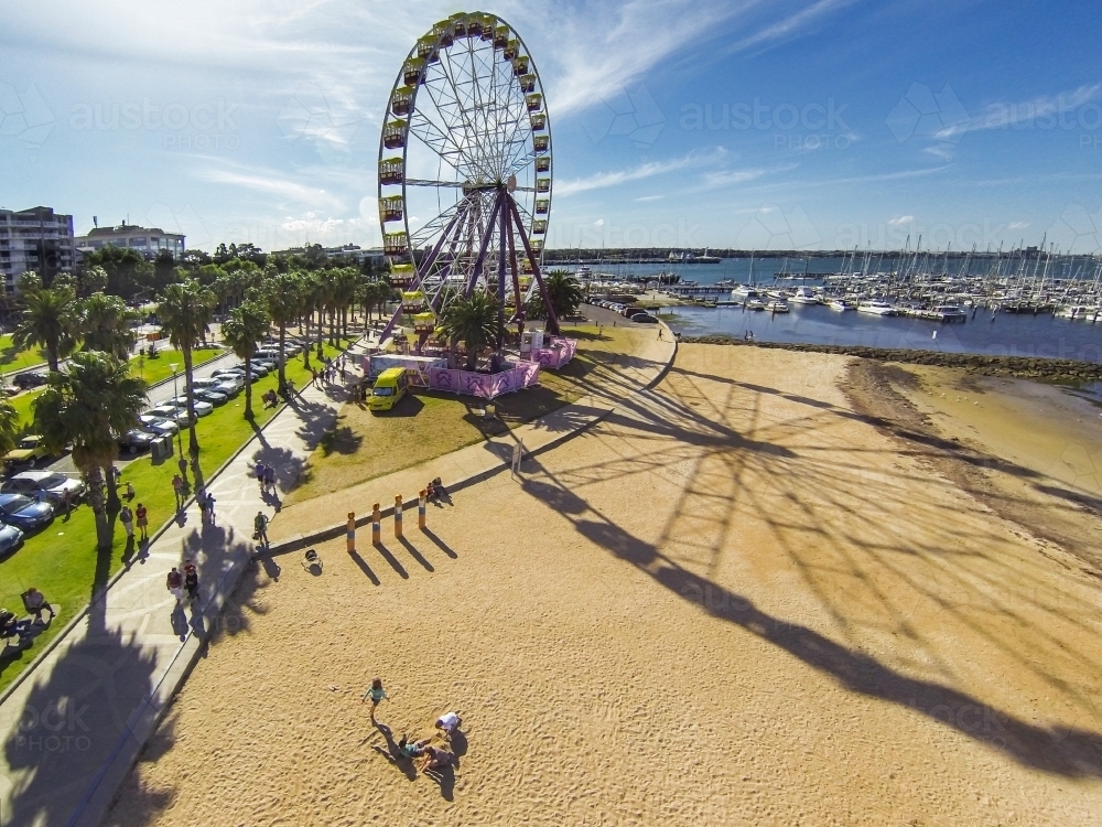 Looking down on a ferris wheel and its long shadow over a beach - Australian Stock Image