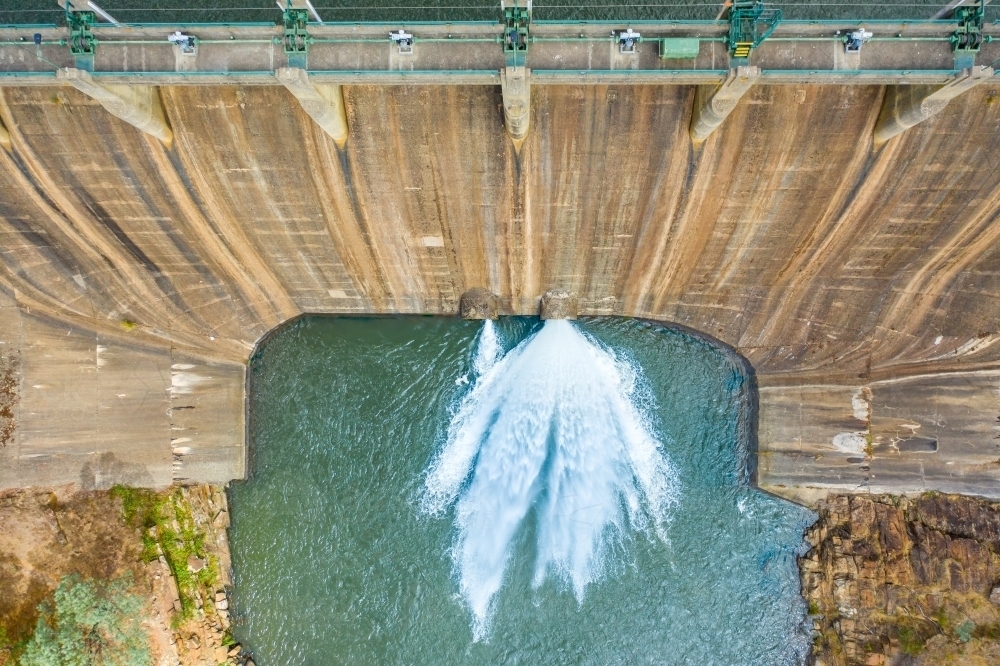 Looking down on a jet of water squirting from the bottom of a dam wall of a reservoir - Australian Stock Image