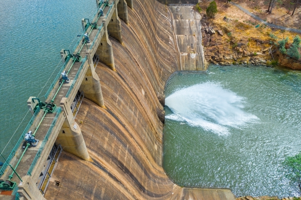 Looking down on a jet of water squirting from the bottom of a dam wall of a reservoir - Australian Stock Image