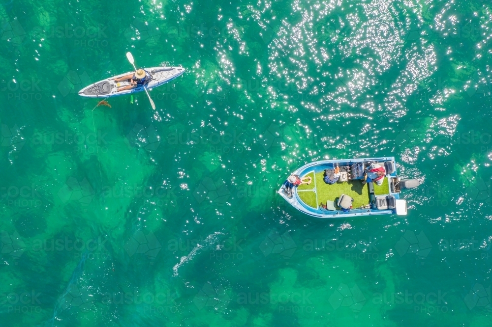 Looking down on a person on a kayak and dinghy on the ocean - Australian Stock Image