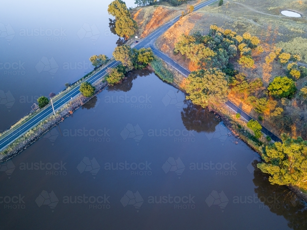 Looking down on a T intersection of a causeway and a road beside a lake - Australian Stock Image