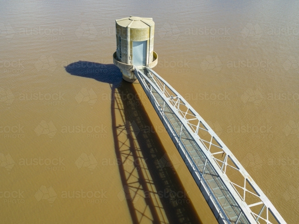 Looking down on a walkway over water leading to a concrete tower - Australian Stock Image