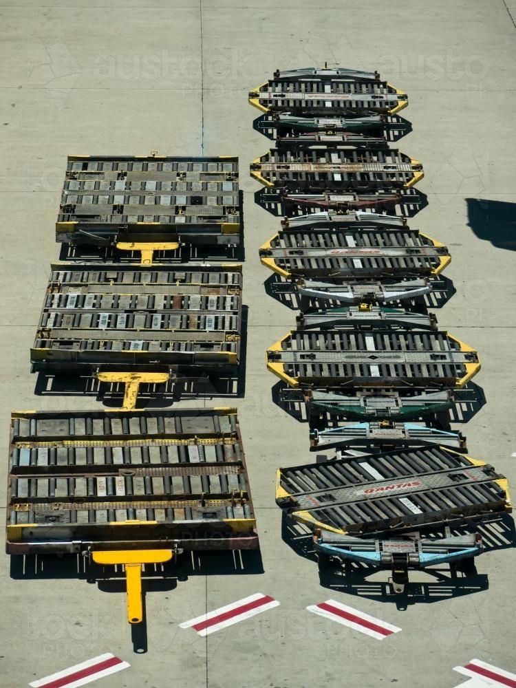 Looking down on aeroplane cargo trolleys parked at an airport - Australian Stock Image