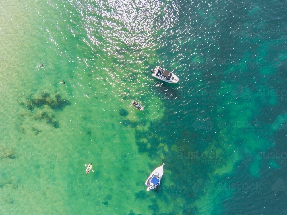 Looking down on boats and canoes afloat on the ocean - Australian Stock Image
