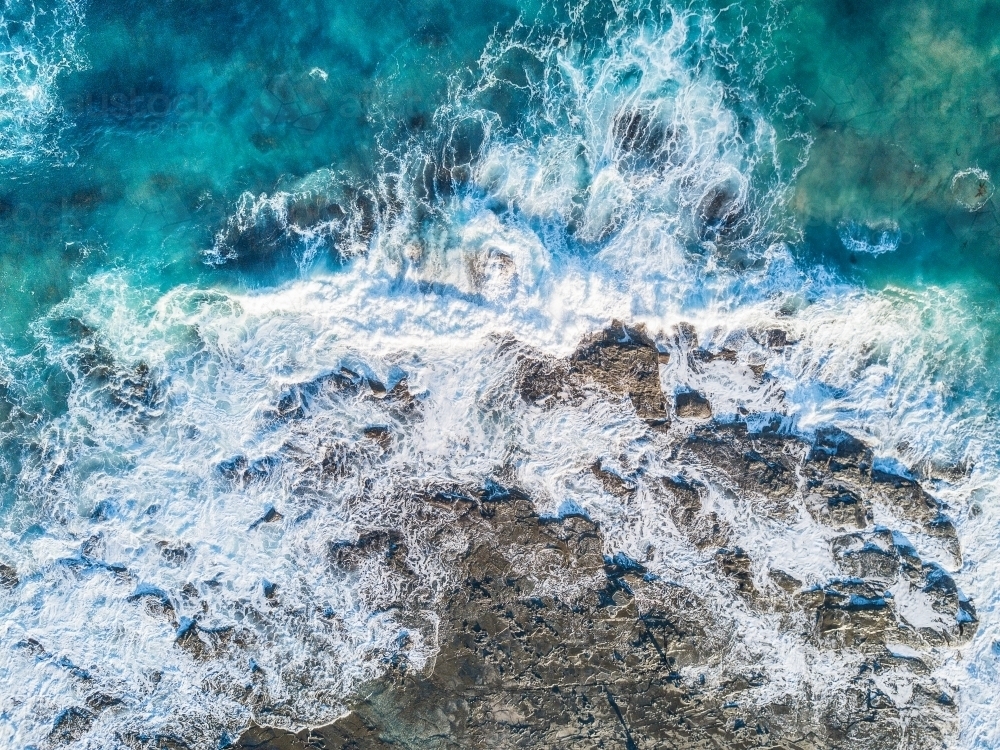 Looking down on large waves breaking on a rocky shore - Australian Stock Image