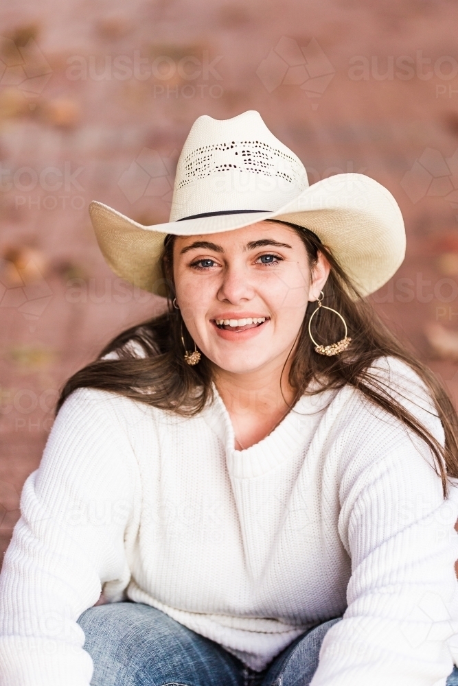 Looking down on teenage girl sitting on path smiling - Australian Stock Image
