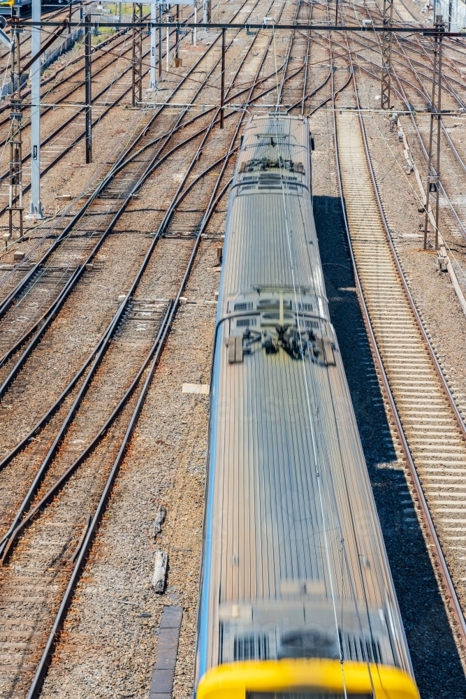 Looking down on the top of a commuter train speeding through a railway yard - Australian Stock Image