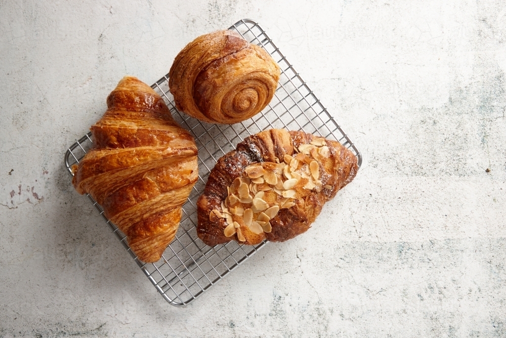 Looking down on three pastries on a cooling rack on marble background - Australian Stock Image