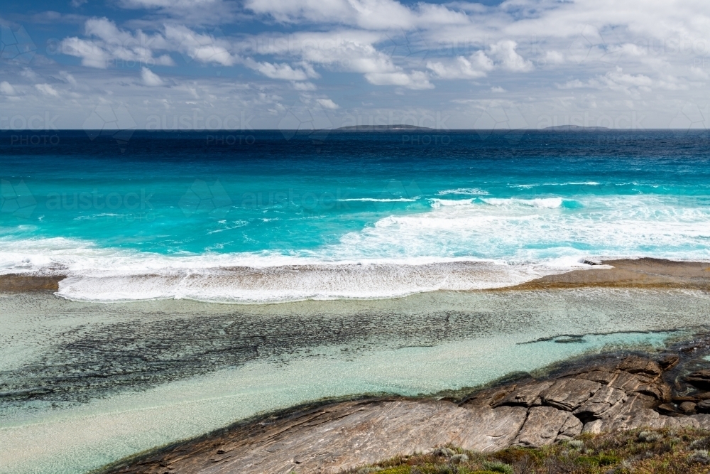 Looking down on turquoise water flowing into a rockpool - Australian Stock Image
